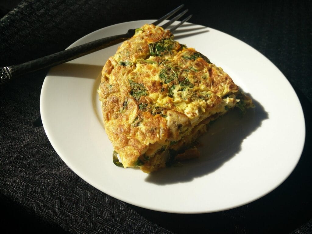 Omelete de micro-ondas com queijo e presunto, feito no micro-ondas, apresentado num prato branco com garfo ao lado.